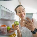 woman looking at her phone while holding an apple